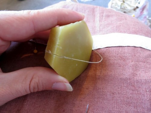 Drawing my thread through the edge of my wax cake to wax it