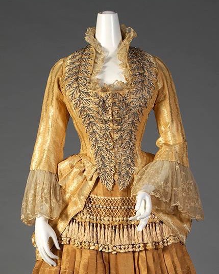 Gold silk dress with tiered, tasseled skirt Label- “Mrs. W. Wilds, Auburn, NY” American, ca. 1879-80, Silverman:Rodgers, KSUM 1983.1.156 ab