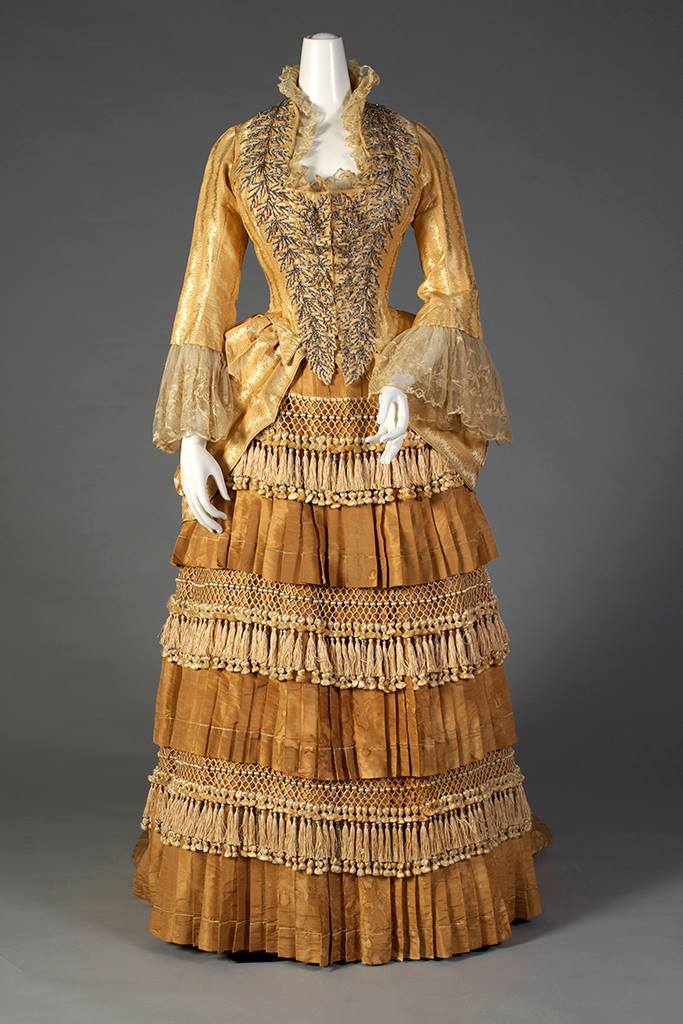 Gold silk dress with tiered, tasseled skirt Label- “Mrs. W. Wilds, Auburn, NY” American, ca. 1879-80, SIlverman:Rodgers, KSUM 1983.1.156 ab