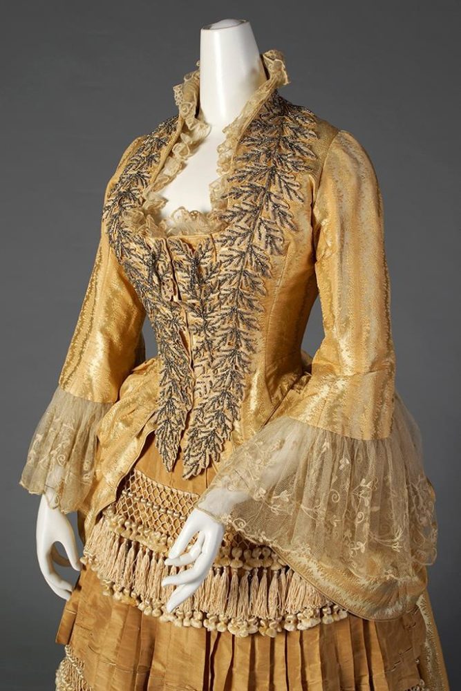 Gold silk dress with tiered, tasseled skirt Label- “Mrs. W. Wilds, Auburn, NY” American, ca. 1879-80, SIlverman:Rodgers, KSUM 1983.1.156 ab