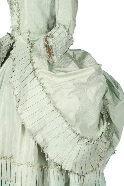 Robe, French, circa 1780, fastening with hooks and eyes, with with box pleated and fly-braid edged robings, fitted back skirts with fixed green silk cords, sold by Kerry Taylor Auctions