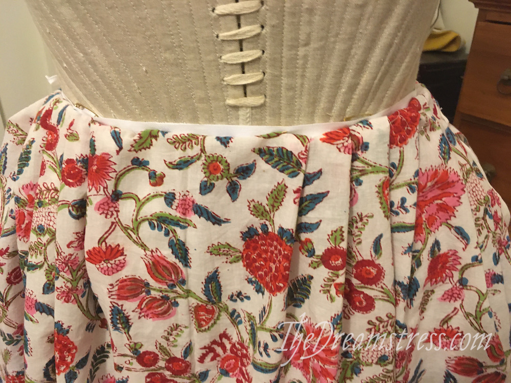 A detail of silver 18th century stays and a brightly coloured floral petticoat