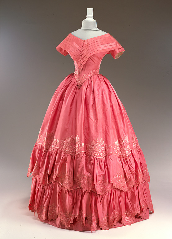 Image shows an 1840s evening dress in carnation pink with a full skirt.