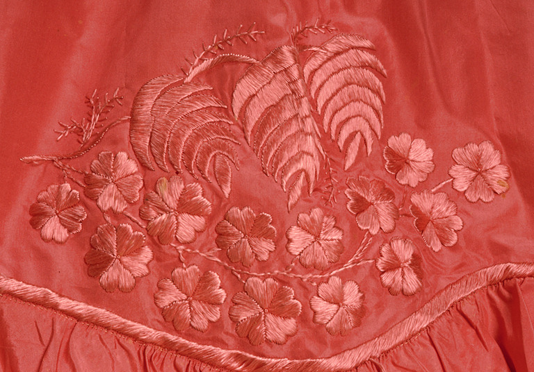Image shows a piece of carnation pink silk embroidered with flowers