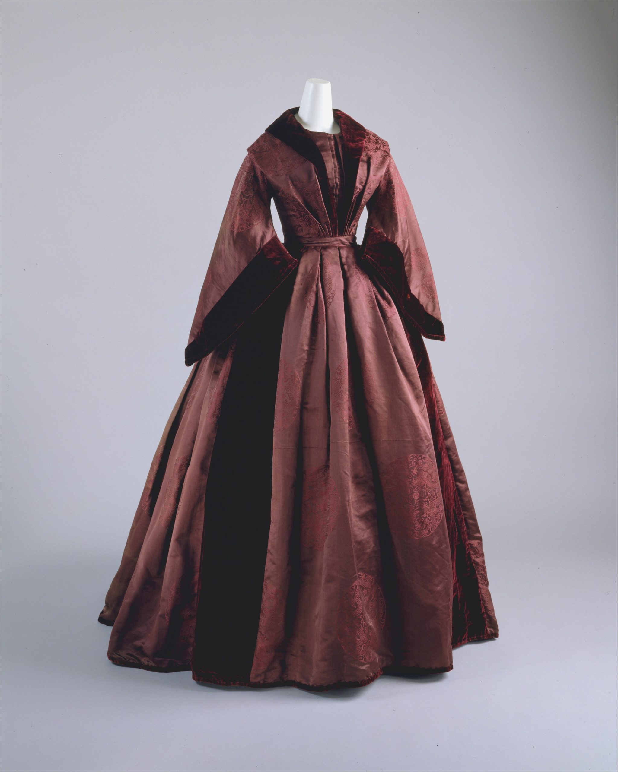 Image shows a dark purple-brown mid 19th century dress from the front