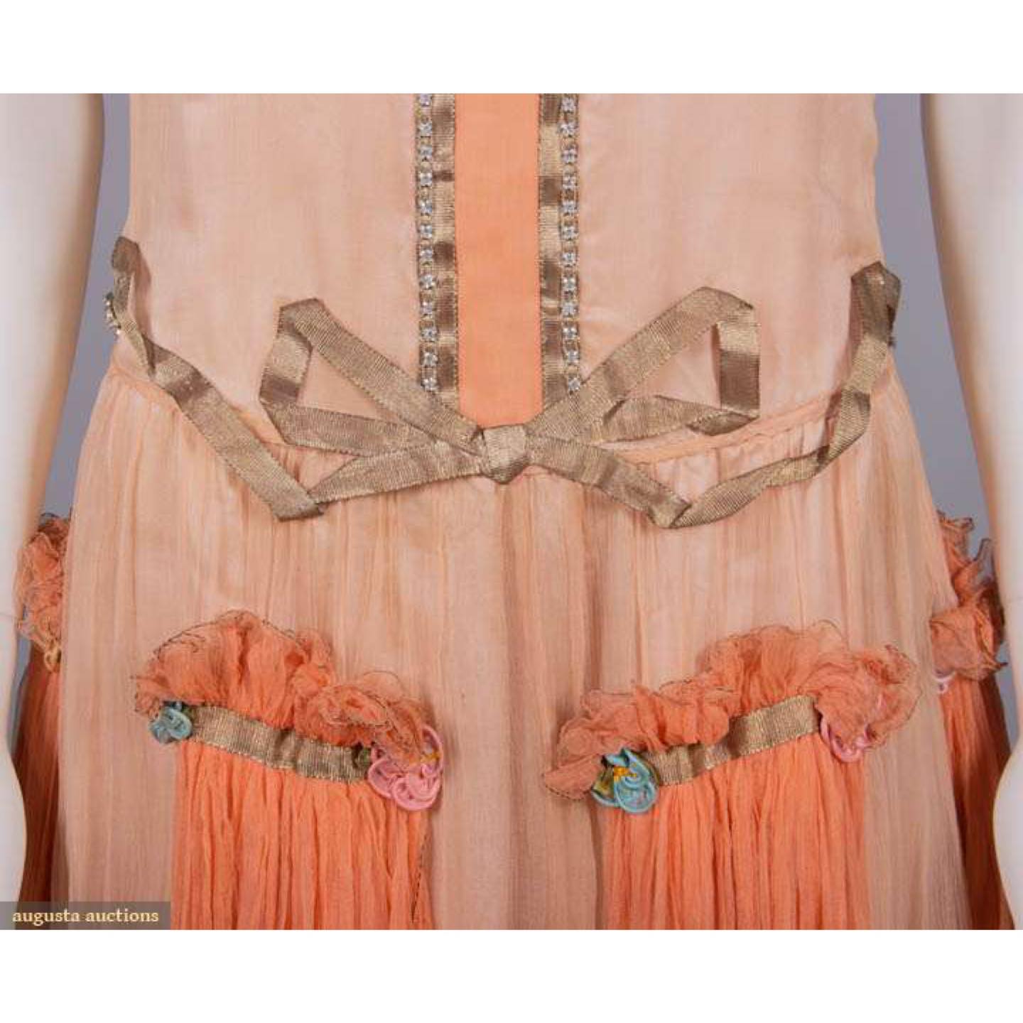 Evening dress, 1920s, Crepe chiffon over silk satin with lame ribbon applique and fine inserted edging, rhinestones, corded silk rosettes and gathered peach chiffon cascades sold by Augusta Auctions, June 2023
